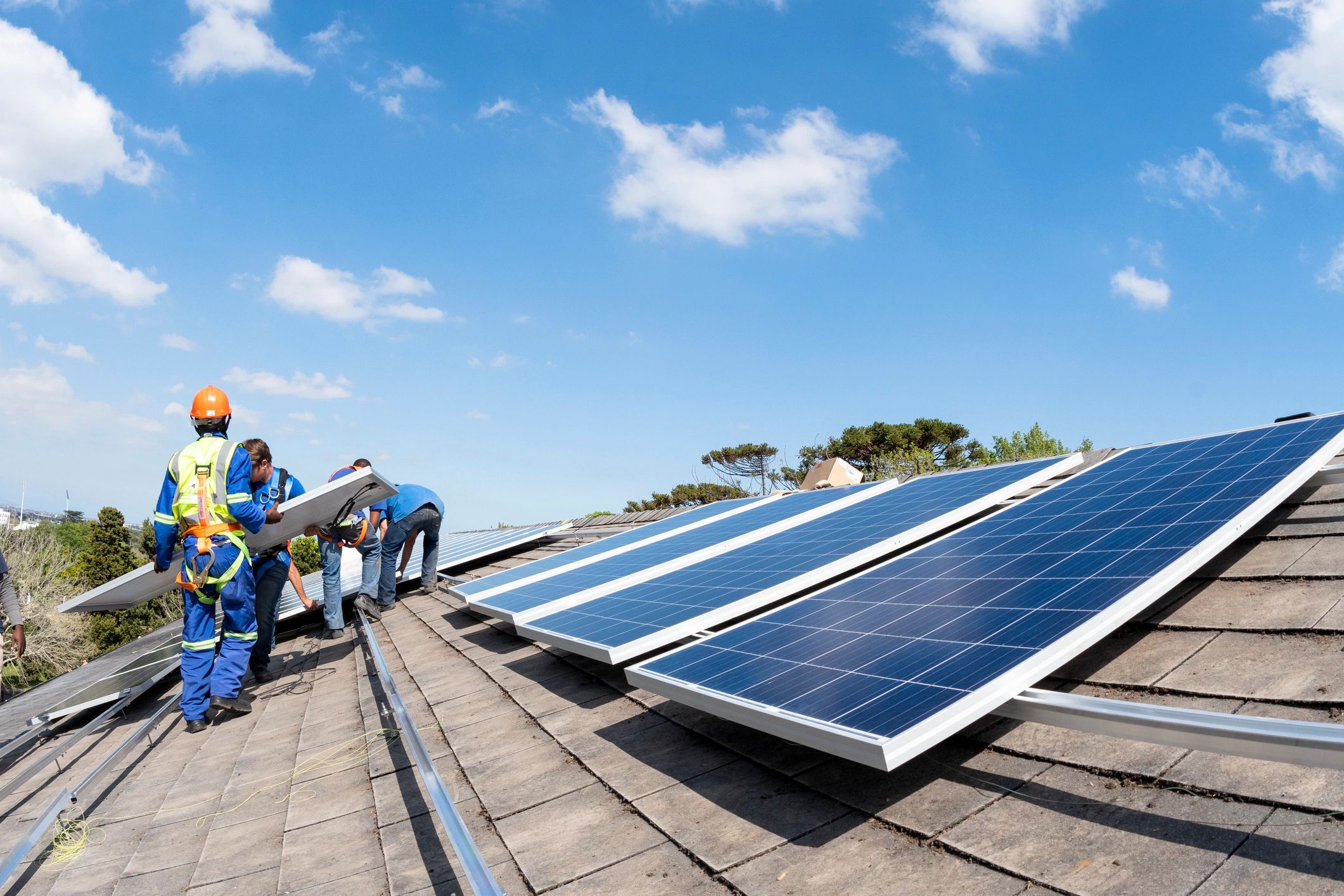 Solar installation team carrying a panel during rooftop work